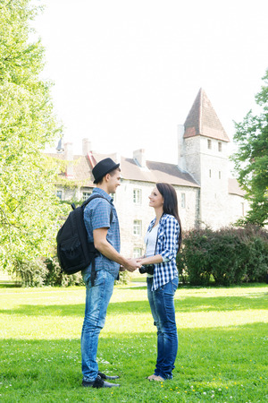 Beautiful traveling couple holding hands in summer park with medieval tower on the background.の写真素材