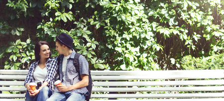 Couple of travelling hipsters: sitting on bench. Holiday, vacation, summer, journey: concept.の写真素材