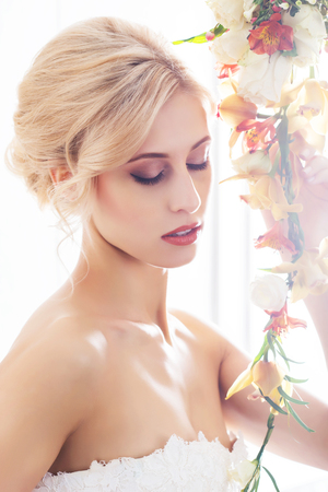 Beautiful, sensual bride in white dress posing with flowers.の写真素材