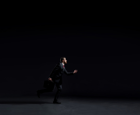 Running businessman over black background. Business, career job concept.の写真素材