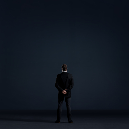Businessman standing over black dramatic background. Business and office, concept.の写真素材