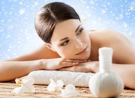 Beautiful, young and healthy woman in winter spa salon. Massage treatment over Christmas background with snow. Traditional medicine and healing concept.の写真素材