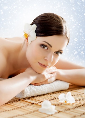 Beautiful, young and healthy woman in winter spa salon. Massage treatment over Christmas background with snow. Traditional medicine and healing concept.の写真素材