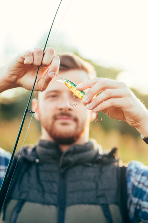 Fisherman with a spinning rod and bait (lure, wobbler)  catching fish on a river. Man on a weekend. Hobby, leisure, active summer and autumn concept. Nature background.の写真素材
