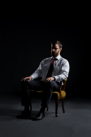 Businessman sitting in armchair over black background. Business and office concept.の写真素材