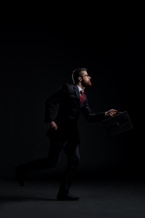 Businessman running hurry over black background. Time, business and office concept.の写真素材