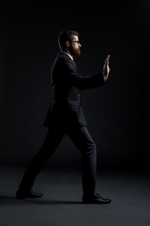 Businessman pushing something imaginary over black background. Business and office concept.の写真素材