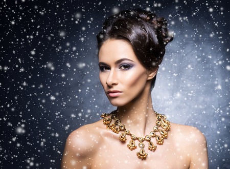 Young, beautiful and rich woman in jewels of platinum and stones over winter Christmas backgroundの写真素材