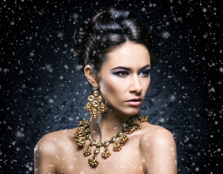 Young, beautiful and rich woman in jewels of platinum and stones over winter Christmas backgroundの写真素材