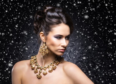 Young, beautiful and rich woman in jewels of platinum and stones over winter Christmas backgroundの写真素材