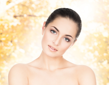 Portrait of young, natural and healthy woman over yellow autumn background.の写真素材