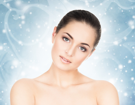 Face of attractive and healthy woman over seasonal Christmas background with a winter snowflakes. Healthcare, spa, makeup and face lifting concept.の写真素材
