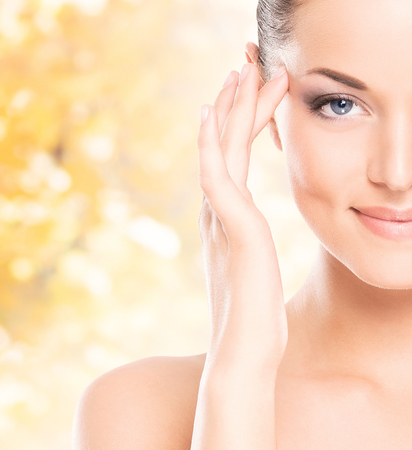 Portrait of young, natural and healthy woman over yellow autumn background.の写真素材