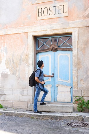 Handsome male tourist entering an old building (hostel, hotel or appartments). Traveling and couchsurfing concept.の写真素材