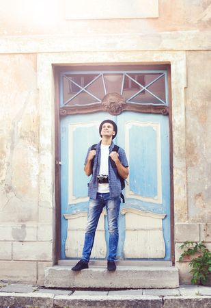 Young travelling hipster: standing near an old door. Vacation, summer, holiday, journey: concept.の写真素材