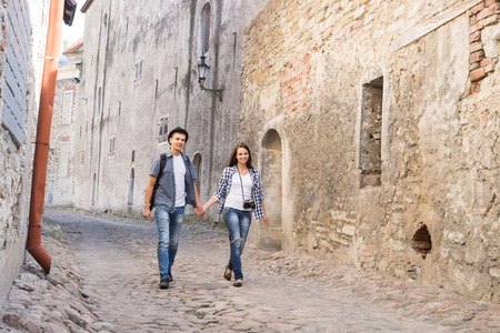 Young travelling couple having a medieval walk on an old street with tile road.の写真素材