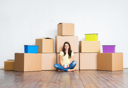 Young girl moving in a new home. Woman with boxes.の写真素材