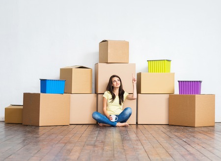 Young girl moving in a new home. Woman with boxes.の写真素材