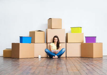 Young girl moving in a new home. Woman with boxes.の写真素材