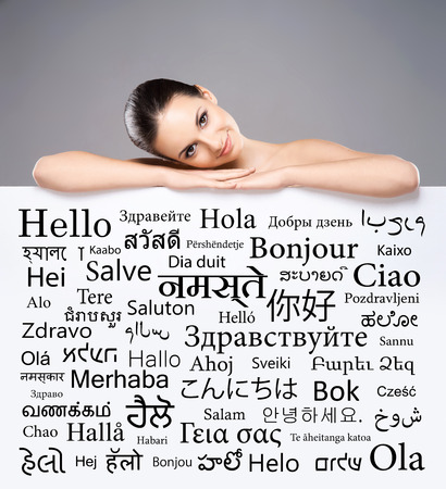 Beautiful girl with a banner of world's different languages over grey background.の写真素材