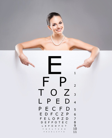 Attractive woman with a banner of test vision table over grey background.の写真素材