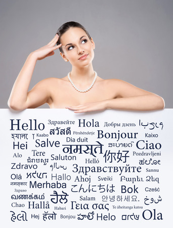 Beautiful girl with a banner of world's different languages over grey background.の写真素材