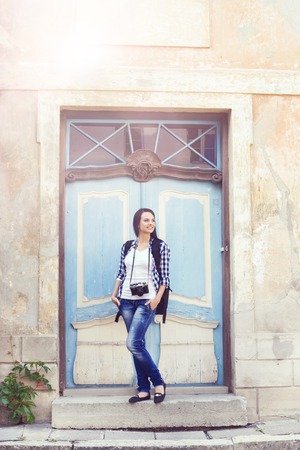 Young  traveller girl: staying near an old door. Vacation, summer, holiday, journey: concept.の写真素材