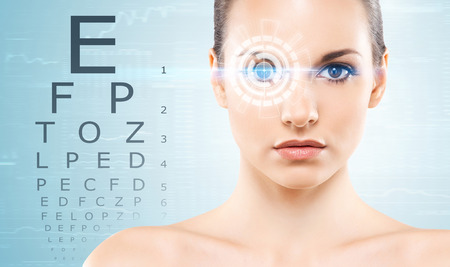 Beautiful woman with laser hologram and test vision table over cyan background.の写真素材