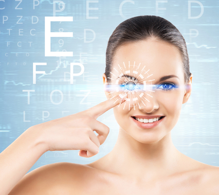 Beautiful woman with laser hologram and test vision table over cyan background.の写真素材