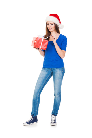 Young and attractive teenager girl with a Christmas present isolated on white backgroundの写真素材