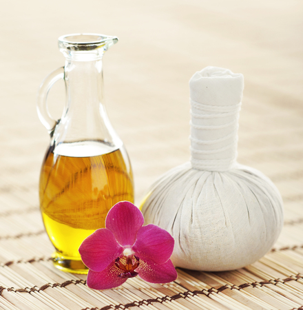 Orchid, jar with oil and massaging ball on woven bamboo mat over isolated background.の写真素材