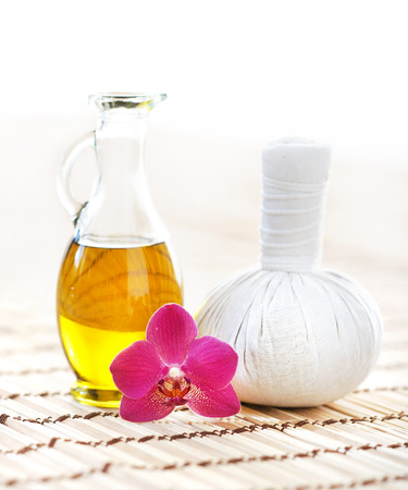 Orchid, jar with oil and massaging ball on woven bamboo mat over isolated background.の写真素材