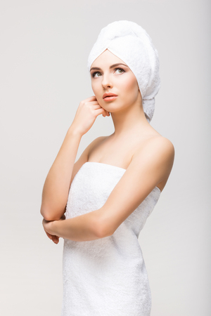 Young, beautiful and natural woman wrapped in towel isolated on whiteの写真素材