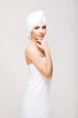 Young, beautiful and natural woman wrapped in towel isolated on whiteの写真素材