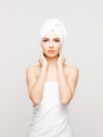 Young, beautiful and natural woman wrapped in towel isolated on whiteの写真素材