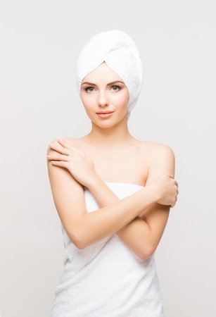 Young, beautiful and natural woman wrapped in towel isolated on whiteの写真素材