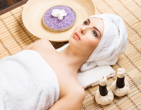 Beautiful, young and healthy woman in spa salon on bamboo mat. Spa, health and healing concept.の写真素材