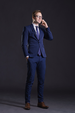 Young and confident business man. Businessman in suit over dark background.の写真素材