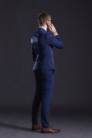 Young and confident business man. Businessman in suit over dark background.の写真素材