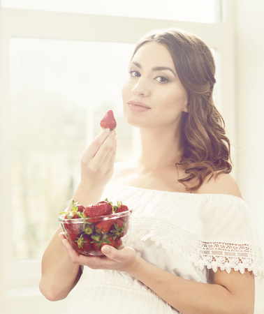 Beautiful and young girl eating strawberries.の写真素材