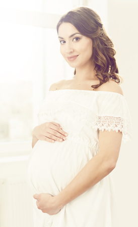 Beautiful pregnant woman in white dress. Motherhood, pregnancy, maternity concept.の写真素材