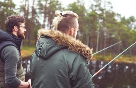 Fisherman with a spinning rod catching fish on a river. Man on a weekend. Hobby, leisure and active summer and autumn concept. Rural background.の写真素材