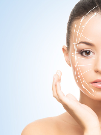 Portrait of beautiful, young woman with a perfect skin and arrows on her face. Face lifting, make-up, plastic surgery and skin care concept.の写真素材