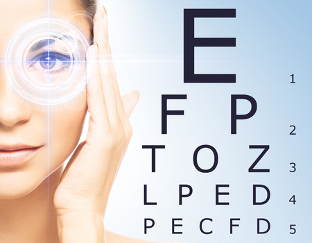 Beautiful woman with laser hologram and test vision table over cyan background.の写真素材