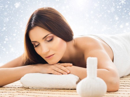Young, healthy and beautiful girl relaxing in winter spa salon. Massage therapy, healing medicine and health care concept. Christmas background.の写真素材