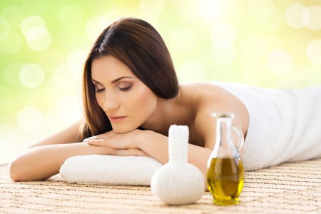Beautiful, young and healthy woman in spa salon. Massage treatment over green summer or spring background. Traditional medicine and healing concept.の写真素材