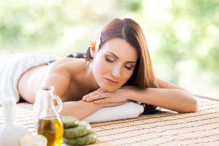 Beautiful, young and healthy woman in spa salon. Massage treatment over green summer or spring background. Traditional medicine and healing concept.の写真素材