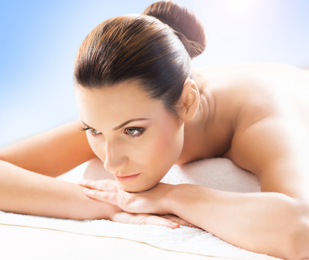Beautiful, young and healthy woman in spa salon. Massage treatment, traditional medicine and healing concept. Blue background.の写真素材
