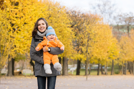 Mother and her toddler son playing in the park. Autumn nature background. Love and family concept.の写真素材