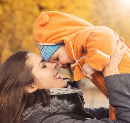 Mother and her toddler son playing in the park. Autumn nature background. Love and family concept.の写真素材